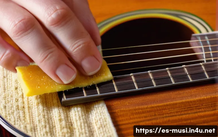 기타 핑거보드 관리 - A close-up scene of a musician&rsquo;s hand carefully cleaning a rosewood guitar fingerboard with a soft m...